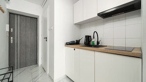 A modern kitchen with white cabinets, a wooden countertop, a black faucet, and a coffee maker. - RentPlanet - Studio Obozowa (Warsaw)