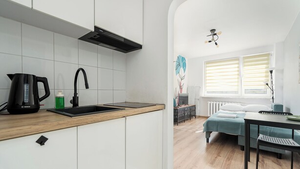 A modern kitchen with white cabinets, a Bosch kettle, and a sink. - RentPlanet - Studio Obozowa (Warsaw)