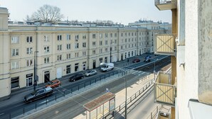 A row of buildings with a tram line and parked cars. - RentPlanet - Studio Obozowa (Warsaw)
