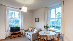 Un salon confortable avec un téléviseur, un canapé et une table à manger avec des chaises.