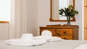 Un lit bien fait, avec du linge de lit blanc et une serviette pliée posée sur le côté.