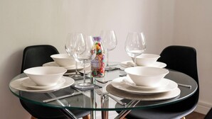 A round glass table with white bowls and wine glasses set for six. - Freya`s Flat with Free Parking (Leicester)