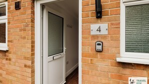 A brick building with a white door, a number '4' sign, a security device, and a 'Travel Fox' logo. - Freya`s Flat with Free Parking (Leicester)