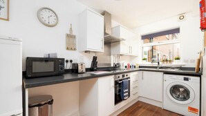 A compact kitchen with a microwave, toaster, oven, and washing machine. - Freya`s Flat with Free Parking (Leicester)