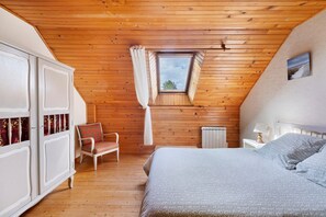 A bedroom with a sloped ceiling, a window, a bed, a chair, and a wardrobe. - Ty kreiz – 500 m from the beach (Plomodiern)