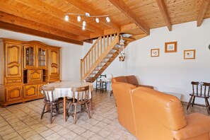 A wooden dining area with a table and chairs, a sofa, and a staircase. - Ty kreiz – 500 m from the beach (Plomodiern)