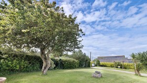 Un giardino con un albero grande, una fioriera in legno e un edificio sullo sfondo.