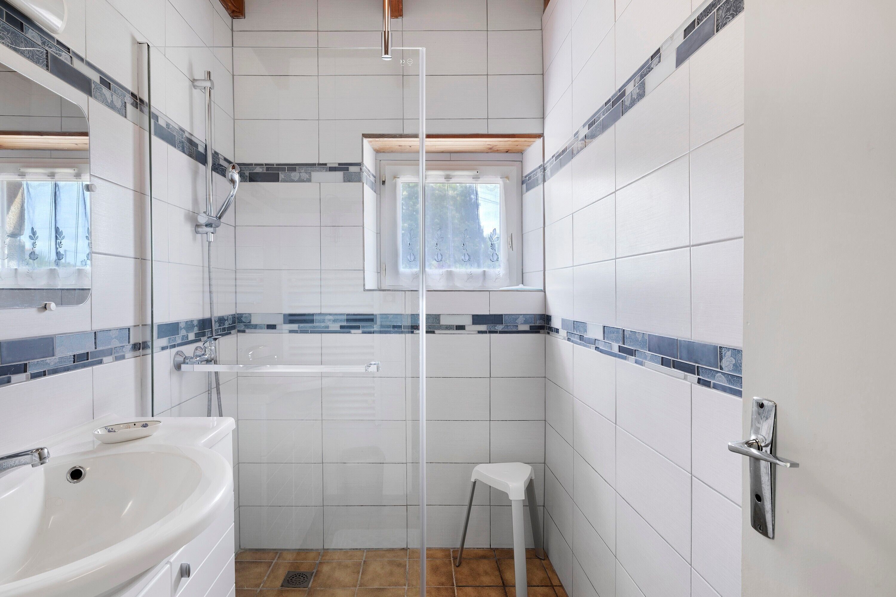 A bathroom with a shower, a sink, and a window.