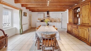 Ein Essbereich mit Holzboden, gefliestem Boden, einem Tisch mit Stühlen und einer Schrank mit Regalen.