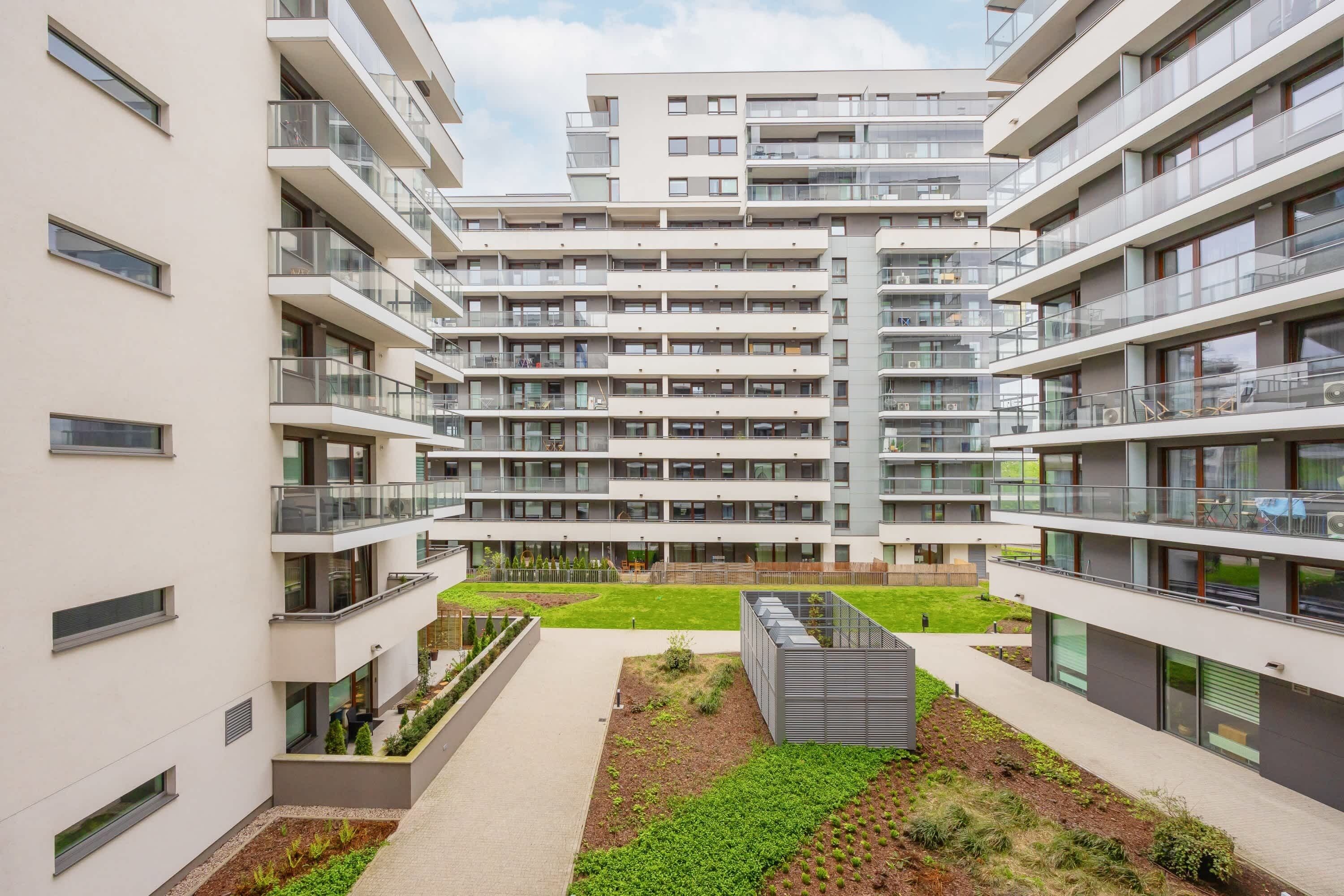 A modern multi-story residential building with balconies, a central courtyard, and a rooftop garden.