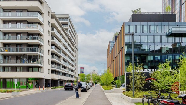 Un immeuble à plusieurs étages doté de balcons, d’une façade moderne en verre et d’une promenade piétonne.