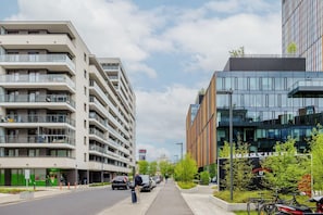 A multi-story building with balconies, a modern glass facade, and a pedestrian walkway. - Modern Studio in Warsaw | Balcony and Workspace (Warszawa)