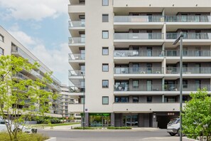 Un immeuble résidentiel à plusieurs étages, doté de balcons, d’un local commercial et d’un espace de stationnement.