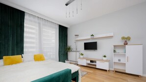 Une chambre moderne avec un lit, une télévision, une armoire blanche et une plante.