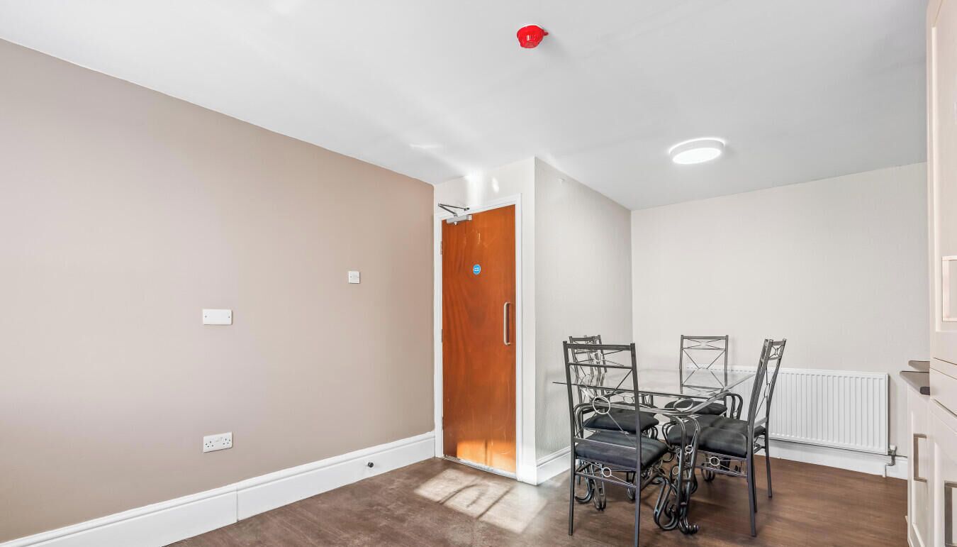 Un coin repas avec une table et des chaises, une porte en bois et un radiateur blanc.