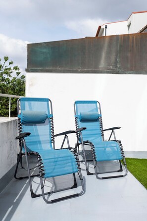 Deux fauteuils de jardin bleus avec des structures noires, placés sur une terrasse.