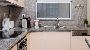 Et kompakt køkken med indbygget ovn, kaffemaskine, brødrister og vask.