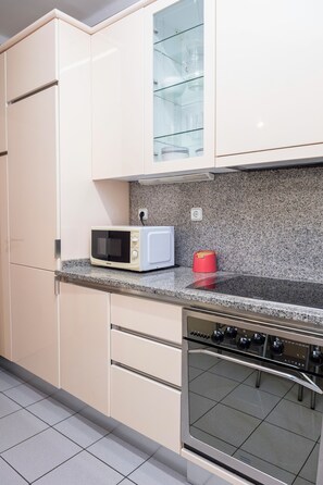 Una cocina con microondas, hervidor rojo y horno de acero inoxidable.