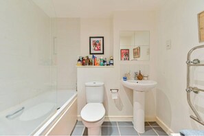 Une petite salle de bain avec une douche à parois de verre, des toilettes blanches, un lavabo sur colonne et un miroir au-dessus du lavabo.