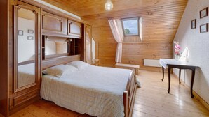 A bedroom with a wooden ceiling, a bed, a bedside table, a window with curtains, and a wall-mounted shelf. - Ty izella – 500m from the sea (Plomodiern)