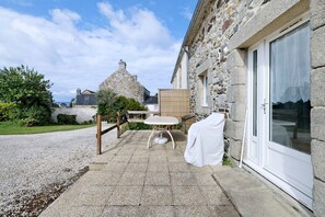 Un bâtiment en pierre doté d’un patio, d’une table et d’un espace salon abrité.