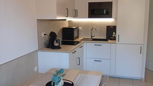 Eine kleine Küche mit weißen Schränken, einer Mikrowelle, einem Toaster und einem Spülbecken.
