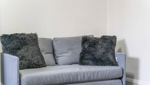 Ein graues Sofa mit weichen, grauen Kissen vor einer schlichten Wand.