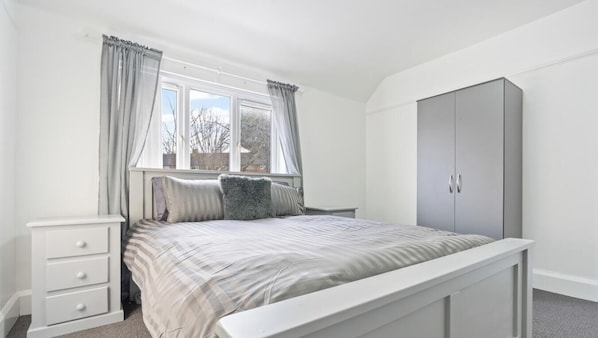 A bedroom with a bed, a nightstand, a wardrobe, and a window with curtains. - Abbie`s House - with free parking! (Nottingham)