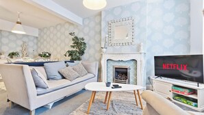 Ein Wohnzimmer mit einer Couch, einem Couchtisch, einem Kamin, einem Fernseher und einem Spiegel.