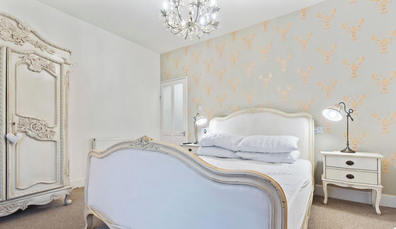 Une chambre à coucher avec un lit, des tables de chevet, une commode et un lustre.