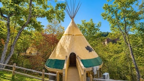A traditional teepee with a wooden entrance and a small porch area.