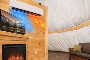 A room with a fireplace, a mounted TV, and a tent-like structure. - Buffalo Run Tepee | Near Dollywood | Resort Access (Sevierville)
