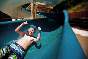 A person sliding down a water slide. - Unique Glamping + Resort Fun access •Sleep 4 (Sevierville)