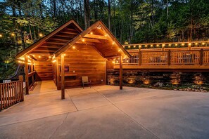A wooden cabin with a porch, a bench, and a sign indicating a 24-hour service. - Unique Glamping + Resort Fun access •Sleep 4 (Sevierville)