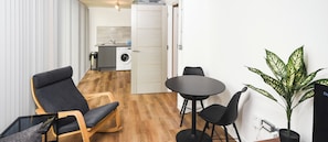 Un espacio habitable compacto con comedor, sofá, mesita y cocina equipada con lavadora.