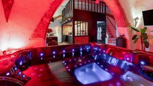 Ein Wellnessbereich mit Whirlpool, einer Backsteinwand und einer Treppe, die zu einer erhöhten Ebene führt.