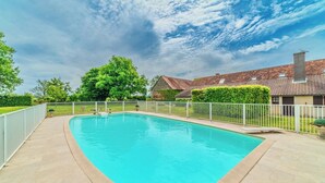 A rectangular swimming pool with a white fence, surrounded by a paved deck, with a house and greenery in the background. - Charming farmhouse with swimming pool - calm & nature (Gueugnon)
