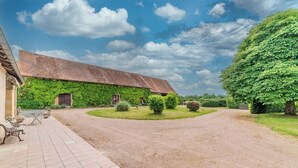 A courtyard with a building covered in green ivy, a paved walkway, and a large tree. - Charming farmhouse with swimming pool - calm & nature (Gueugnon)