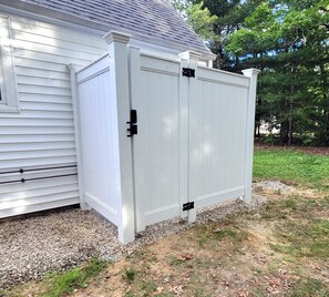 Une porte en métal blanc, fixée à une maison dont l’allée est recouverte de gravier.