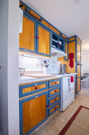 Een keuken met houten kastjes, een witte koelkast en een rode handdoek aan de deur.