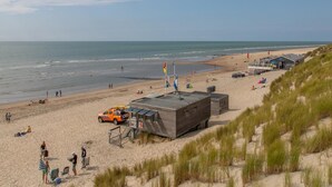 A beach with a lifeguard station, a lifeguard tower, and a dune. - Zeeland Glamping Lodge for 2 (Burgh-Haamstede)
