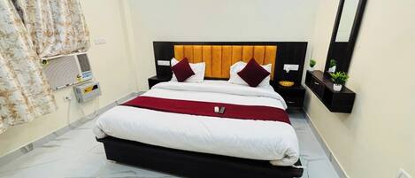 Una habitación de hotel con cama, mesitas de noche, un espejo y un aire acondicionado instalado en la pared.