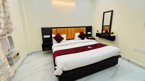 A modern hotel room with a large bed, a bedside table, a mirror, and a wall-mounted shelf.