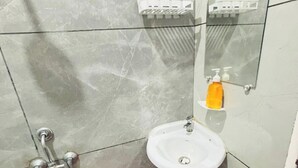 Um banheiro com uma pia branca, um espelho e um balde rosa.