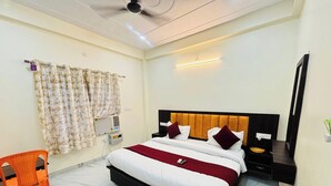 Quarto de hotel com uma cama, uma cadeira, uma mesa de cabeceira, um espelho e um ar condicionado fixado na parede.