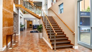 A multi-level interior with a wooden staircase, a reception area, and a view of the outside. - Majestic Hotel Cardiff (Cardiff)