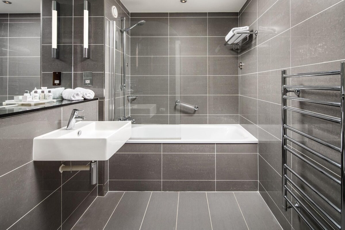 A modern bathroom with a white sink, a bathtub, and a glass-enclosed shower.