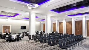 A conference room with rows of chairs, tables, and a large screen. - Majestic Hotel Cardiff (Cardiff)