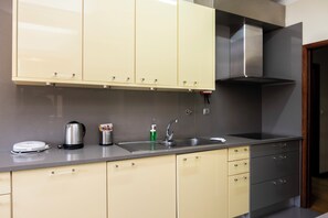 A modern kitchen with a stainless steel sink, a kettle, and a coffee maker.