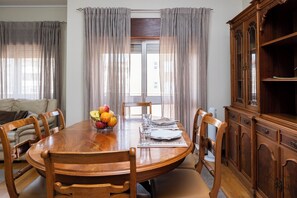 Un comedor con una mesa de madera, sillas, un frutero y un aparador de madera.